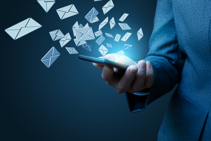 Business person holds smart phone with emails on a blue background