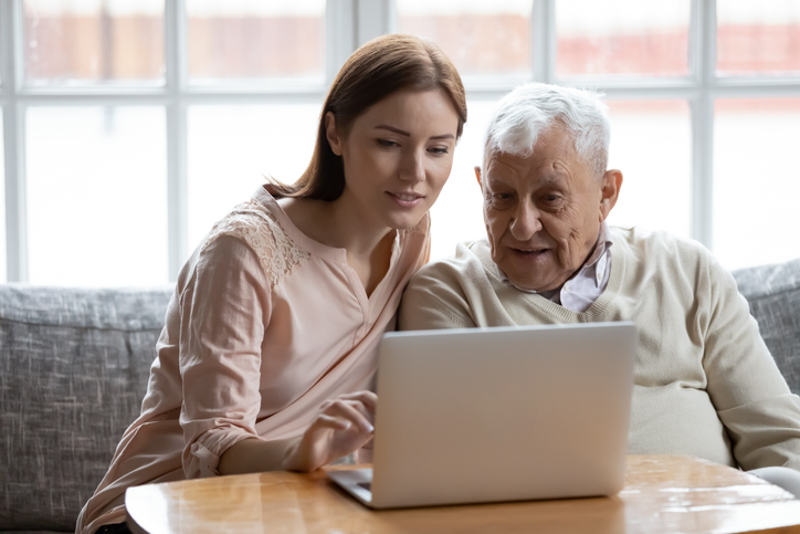 A daughter helps her older father use the computer to search for survivor benefits.